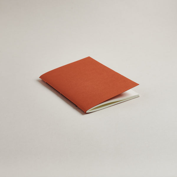 Rust red a6 pocket notebook on a light gray background