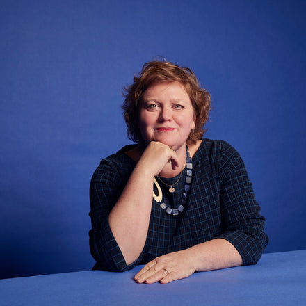 British textile artist Margo Selby, sitting in front of a blue background