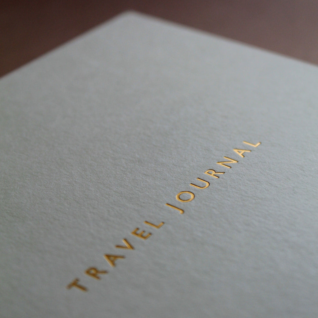 Travel journal with gold text on a textured surface