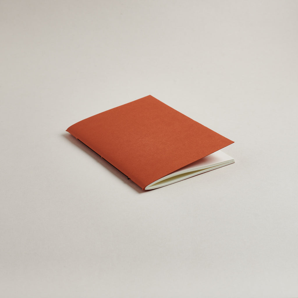 Rust red a6 pocket notebook on a light gray background