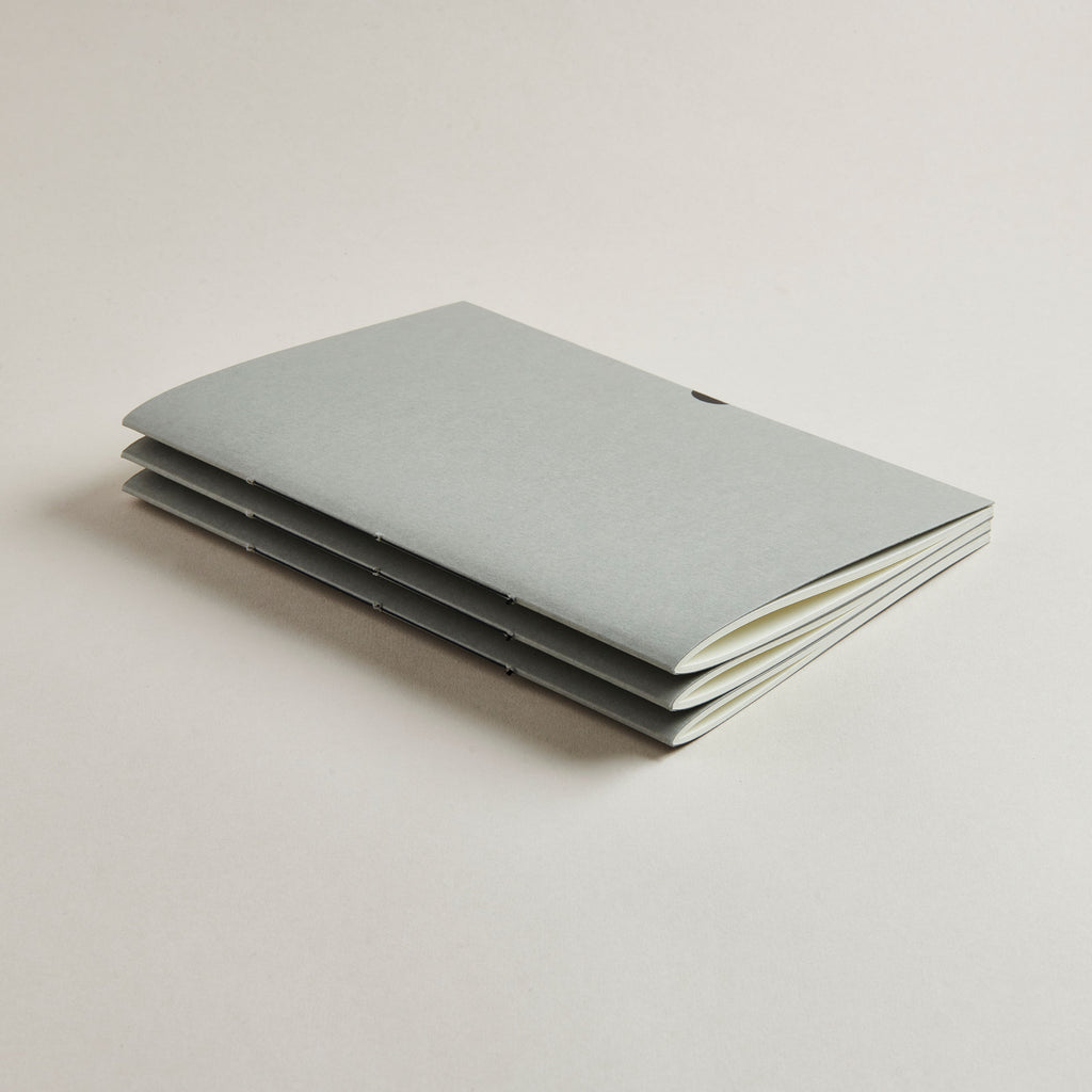 Stack of light gray notebooks on a beige background