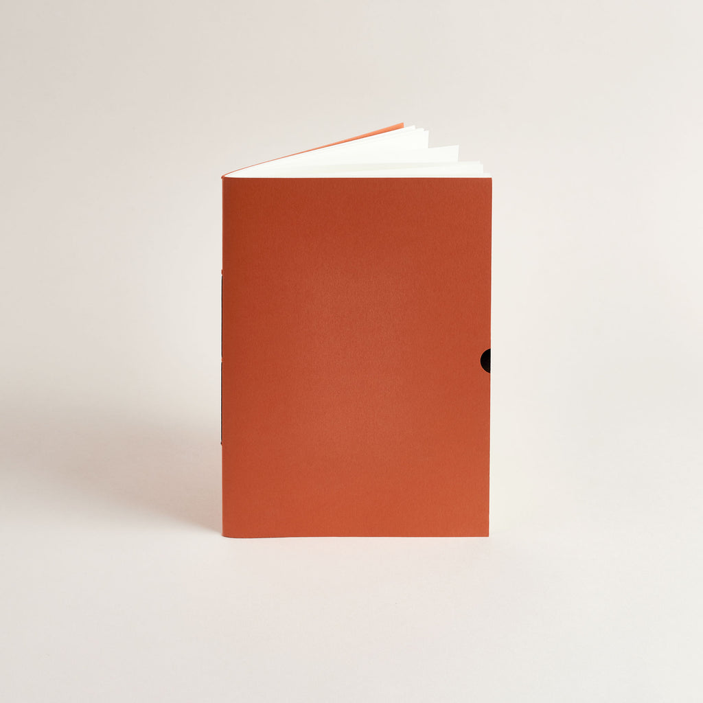Rust red A5 notebook with a white label on a light gray background