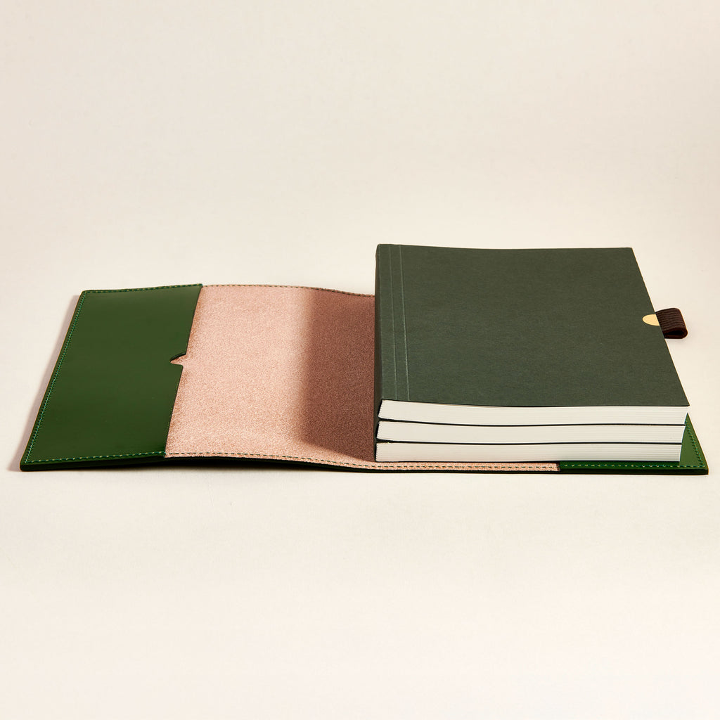 Green leather notebook cover with a bundle of notebooks