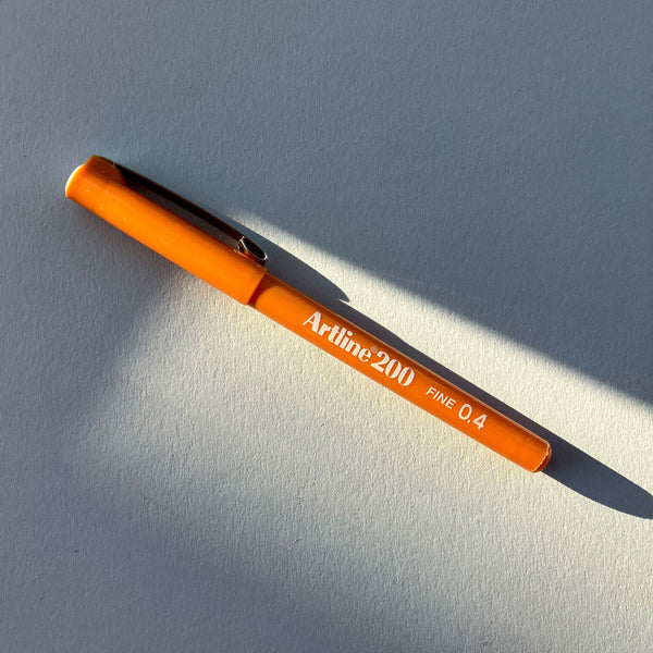 Orange pen with 'Artline 200' branding on a gray background